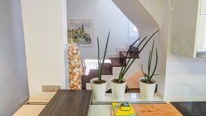 Un comedor con una mesa de madera, tres plantas en macetas y un adorno en la pared.