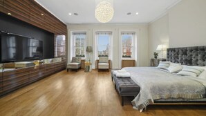 A modern bedroom with a large bed, a TV, and a chandelier. - Magnificent House in Knightsbridge (London)