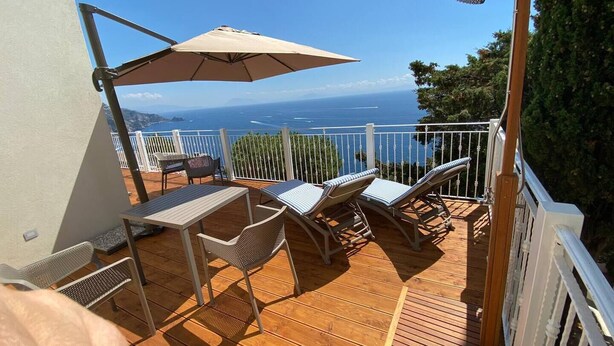 A wooden deck with a table and chairs, a hanging shower, and a view of the sea. - La Miravè holiday home located in Praiano, jewel of the Amalfi Coast. (Praiano)