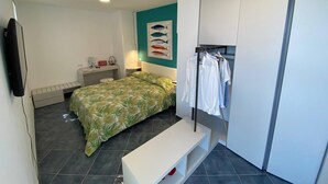 A bedroom with a bed, a bench, a wardrobe, a desk, and a wall-mounted TV. - La Miravè holiday home located in Praiano, jewel of the Amalfi Coast. (Praiano)