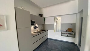 A modern kitchen with grey cabinets, a black tiled floor, and a built-in oven. - La Miravè holiday home located in Praiano, jewel of the Amalfi Coast. (Praiano)