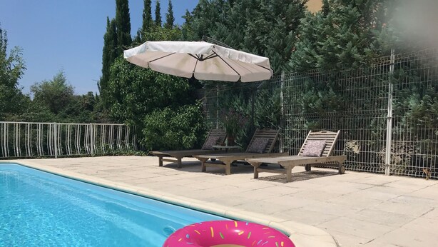 Une piscine avec des chaises longues et un parasol.