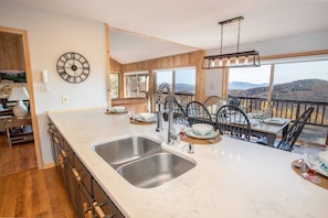 A kitchen with a large island, double sink, and dining area with a view. - Expansive Home on Beech Mountain (Beech Mountain)