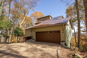 Uma casa térrea com garagem, cercada por árvores com folhagem outonal.