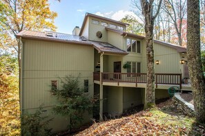 A two-story house with a balcony, surrounded by trees and a leaf-covered ground. - Expansive Home on Beech Mountain (Beech Mountain)