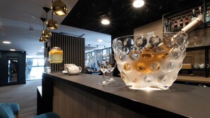 Zona de bar con un gran bol de hielo que contiene vasos y botellas, una tetera blanca y una estantería con botellas.