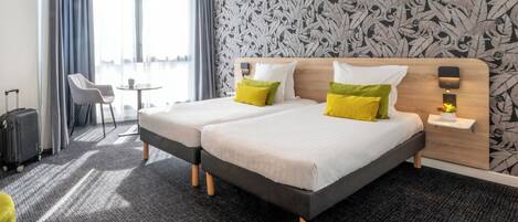 Una habitación de hotel con dos camas, una mesita, una silla y una maleta.