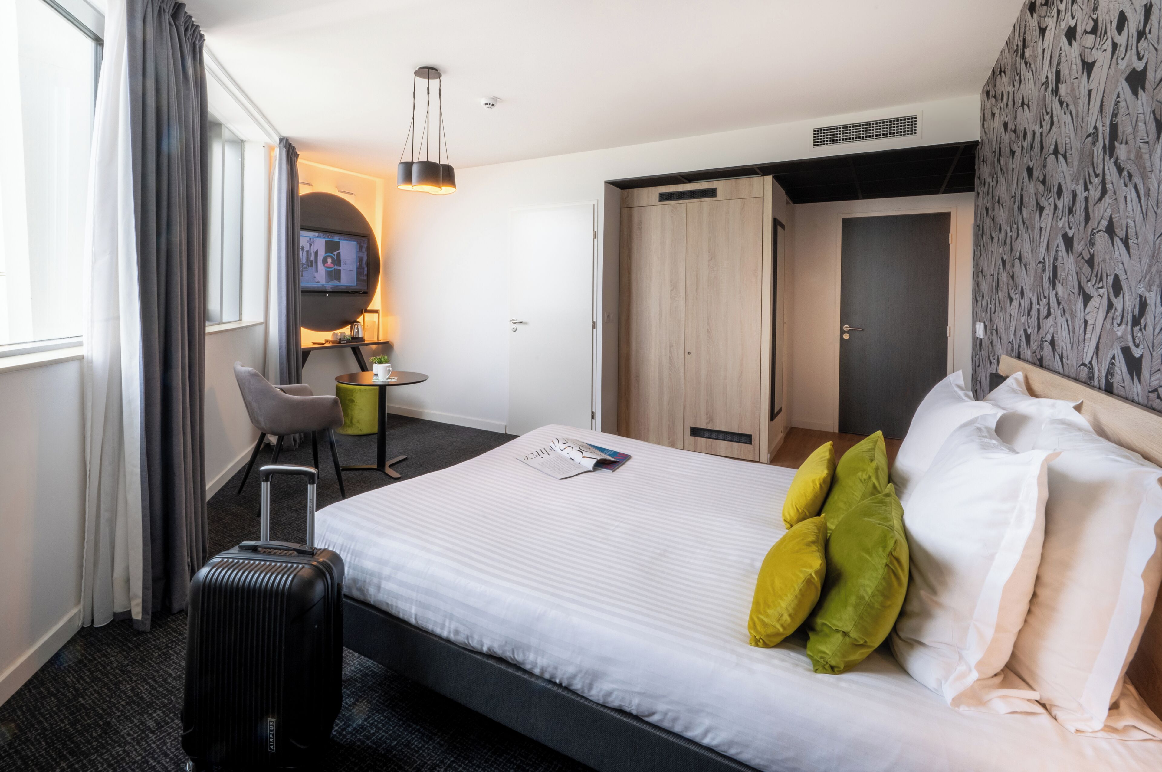 Una camera d'albergo con un letto, una scrivania con una sedia, una televisione e un armadio.