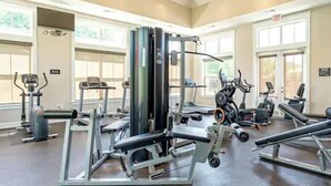 Een fitnessruimte met diverse trainingsapparaten, grote ramen en een hoge nok.