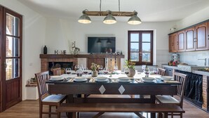 Ein Essbereich mit einem Holztisch, gedeckt für vier Personen, einem Kamin und einem Fernseher über dem Kamin.