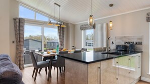 A modern kitchen with a central island, pendant lighting, and a view of the outdoors.