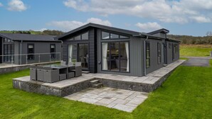 A modern house with a patio, large windows, and a brick foundation.