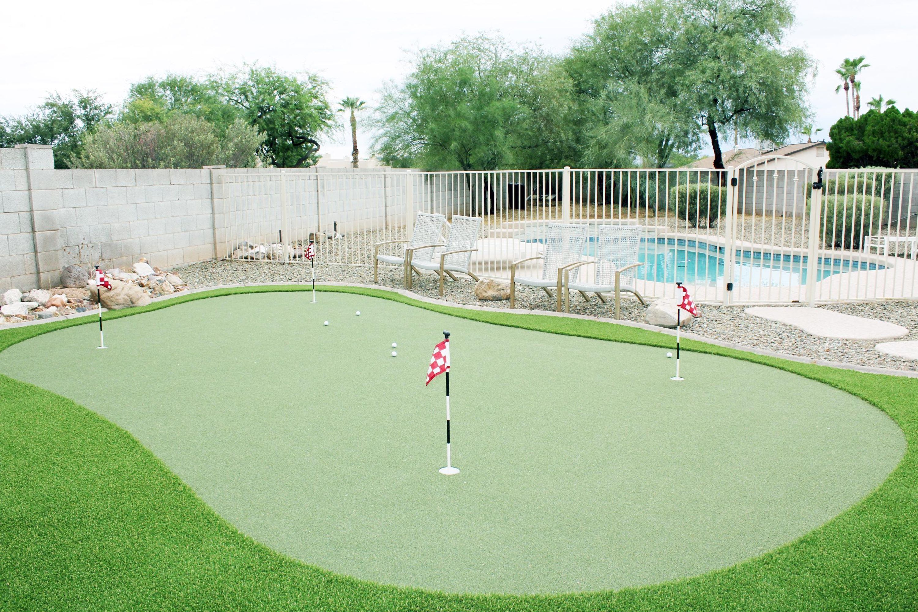 A mini-golf course with a pool and lounge chairs in the background.