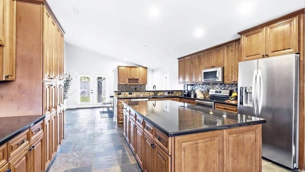 A spacious kitchen with wooden cabinets, a large island, and stainless steel appliances. - The Scott With Heated Pool by Homeslice Stays (Scottsdale)