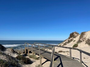 A wooden boardwalk leading to a beach with clear skies and ocean waves. - Grannys Guesthouse (Mira)