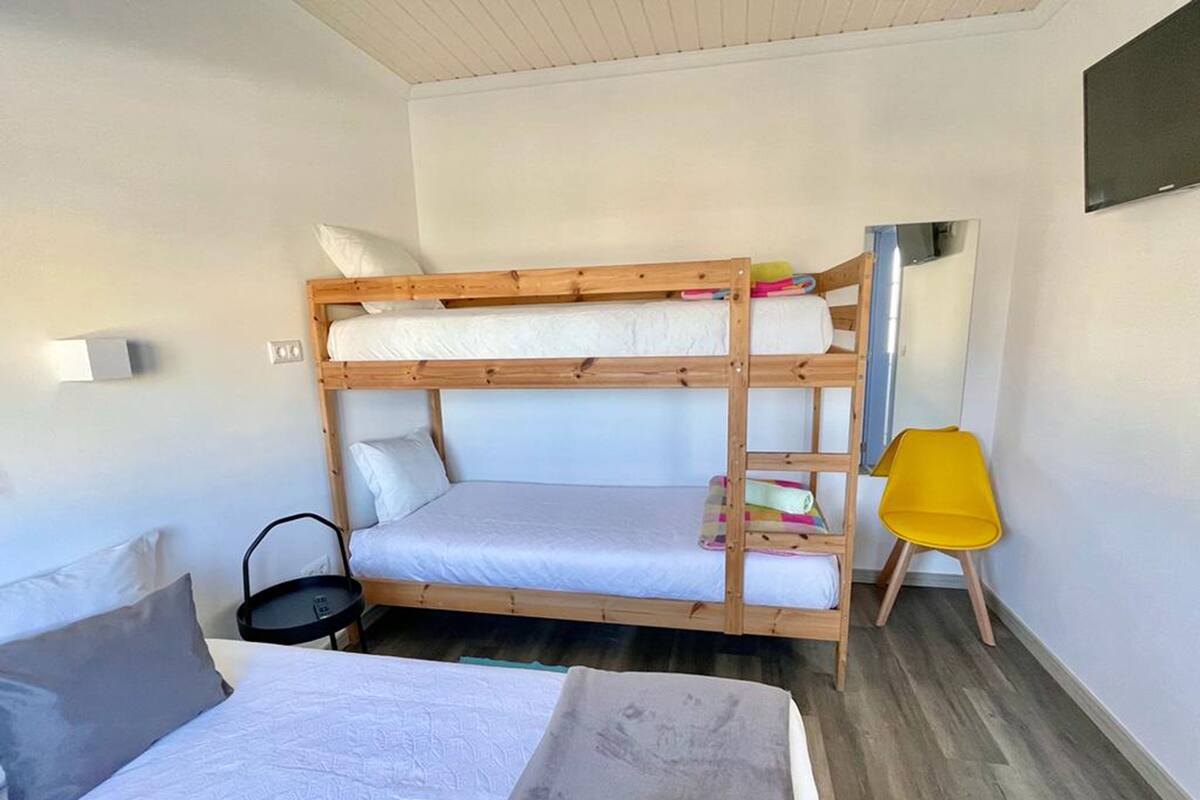 A bunk bed room with a single bed, a chair, and a small table.