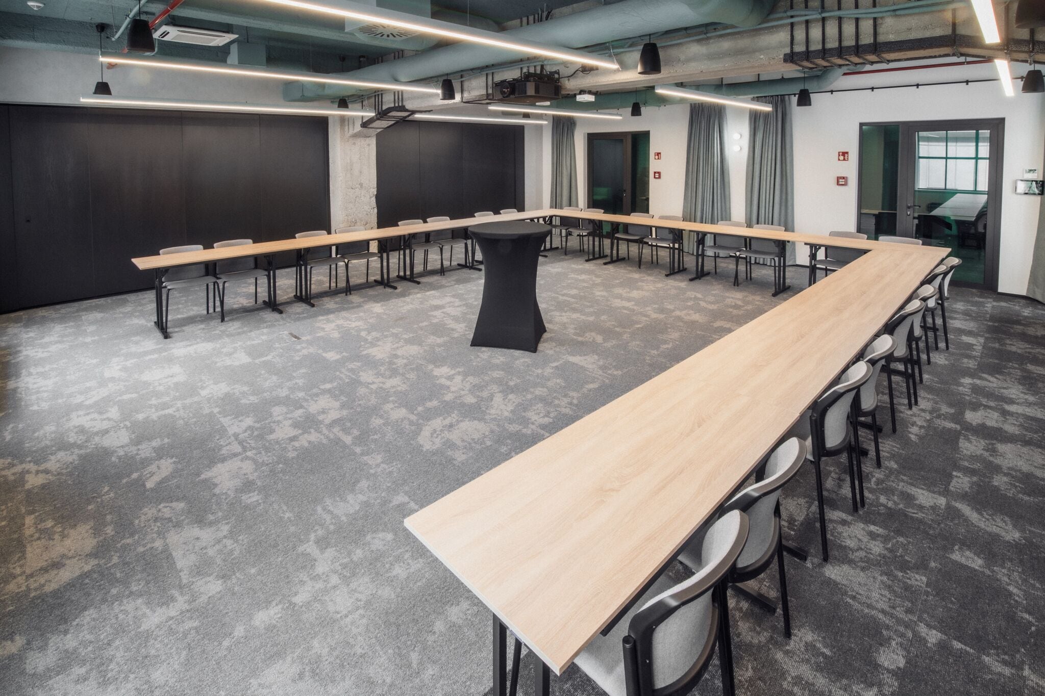 Uma sala de conferências com uma mesa comprida, cadeiras e uma tela de projetor.