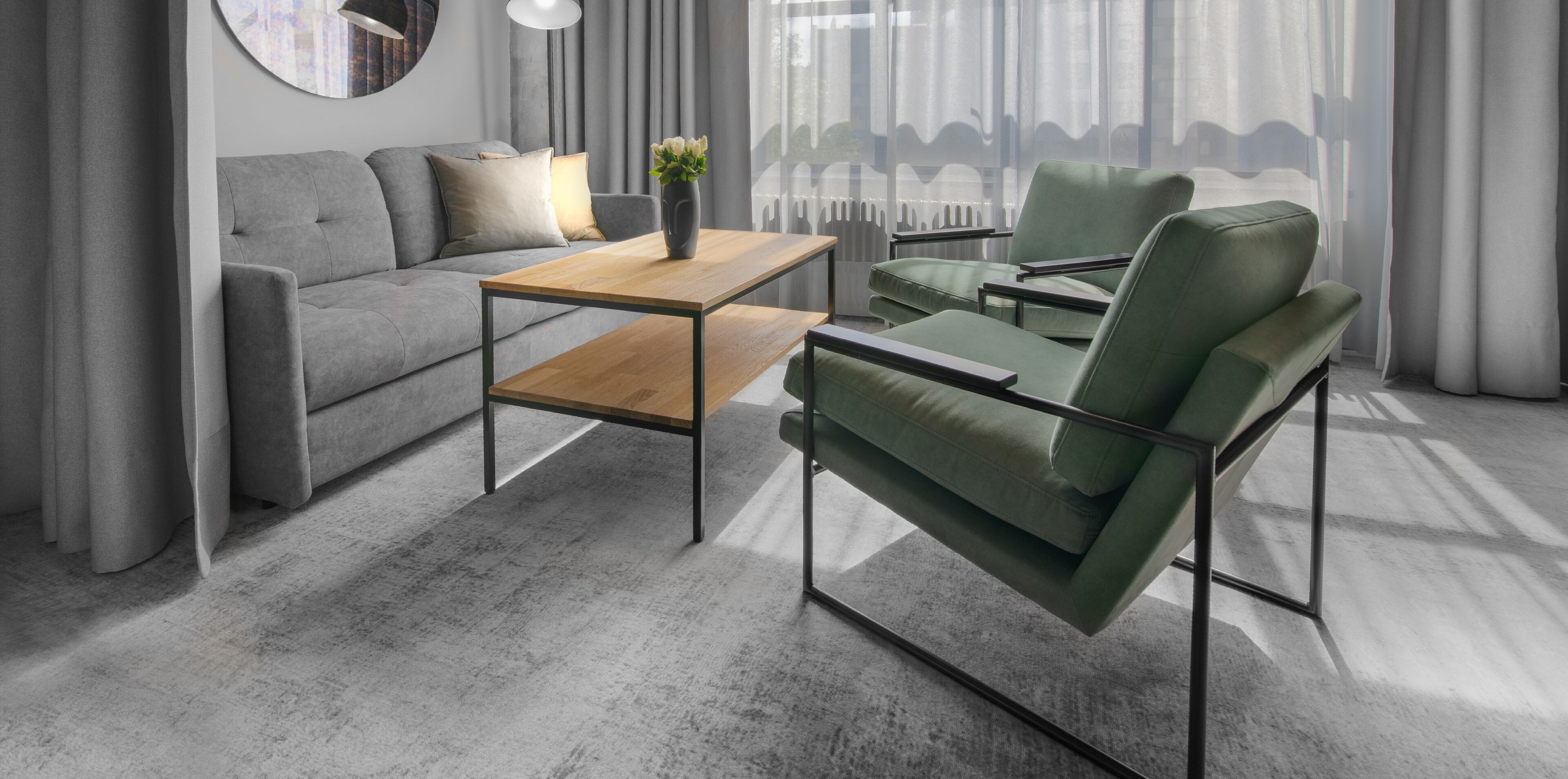A modern living room with a grey sofa, a wooden coffee table, and a green armchair.