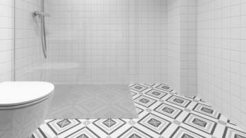 A bathroom with white tiled walls and floor, a toilet, and a shower area.