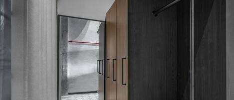 A modern bathroom with a geometric patterned floor, a wooden vanity with black handles, a towel rack, and a shower area with a metal pole.