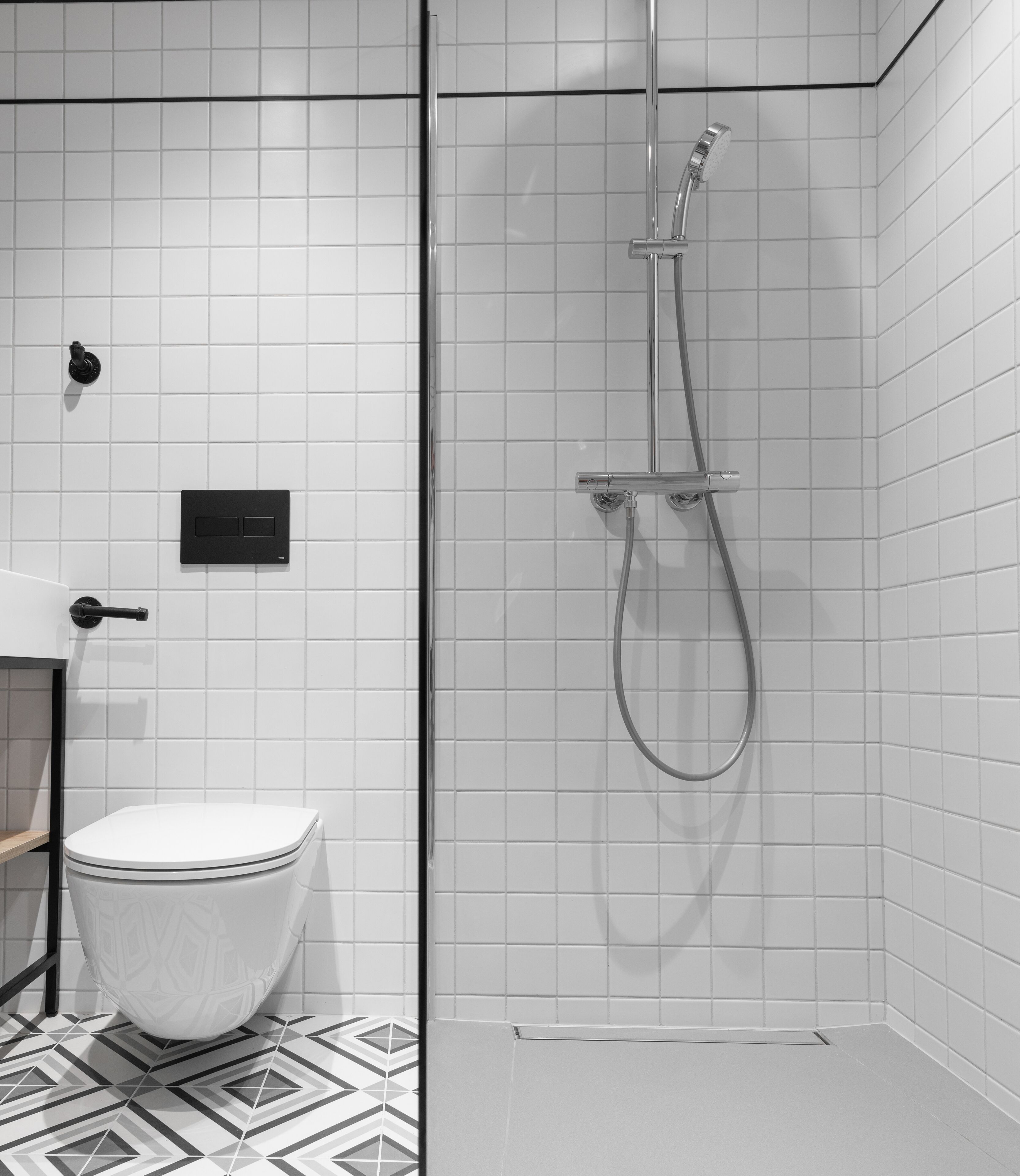 A modern bathroom with a toilet, a shower with a glass door, and a control panel.