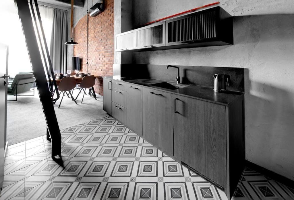 A modern kitchen with a large island, built-in appliances, and a patterned floor.
