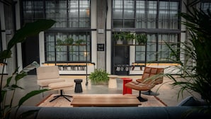Um interior moderno com um sofá, poltronas, uma mesa de centro e uma estante de livros.