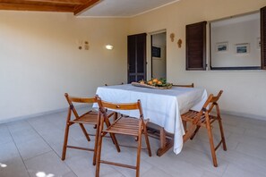 Uma sala de jantar com uma mesa coberta por toalha branca, rodeada por cadeiras de madeira.