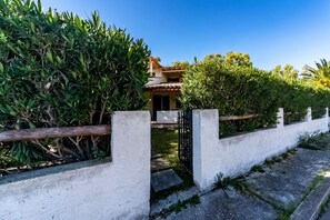 Uma casa com fachada branca, telhado telhado e portão preto.