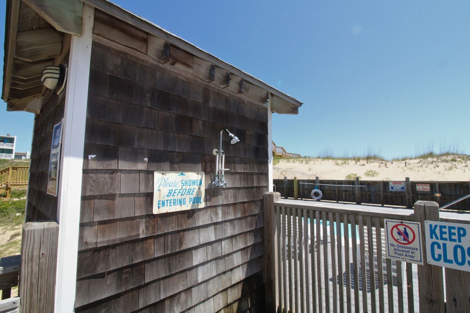 A wooden building with a sign instructing to shower before entering the pool area.
