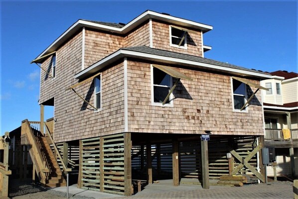 A two-story wooden house with a balcony, a staircase, and a garage. - Whalebone Oceanfront 3 Bedroom Cottage C (Nags Head)