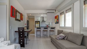 Un appartement moderne comprenant un coin repas, une kitchenette et un salon avec un canapé et un téléviseur.