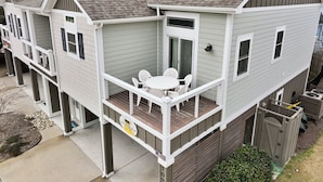A two-story house with a balcony, a small patio, and a garage. - Home on the Banks at Beacon Villas 4 Bedroom Townhouse (Corolla)