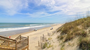 A beach with a wooden staircase leading down to the sand, a sandy beach with a wooden fence, and the ocean in the background. - Home on the Banks at Beacon Villas 4 Bedroom Townhouse (Corolla)
