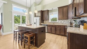 Une cuisine moderne avec des meubles en bois foncé, un plan de travail en granit et des luminaires suspendus.