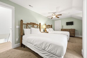 A bedroom with two beds, a ceiling fan, a dresser, and a TV.