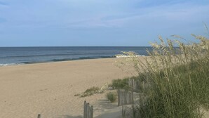 A sandy beach with ocean waves, a wooden fence, and tall grass. - Amina's Cottage 3 BR in KDH + Pets Stay Free (Kill Devil Hills)
