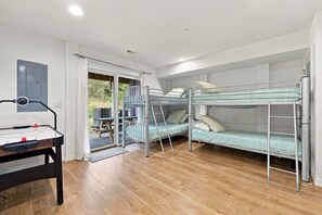A room with bunk beds, a table with a foosball table, and a door leading outside.