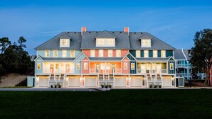 A multi-story residential building with a symmetrical facade, multiple windows, and a central entrance with steps. - Sea Therapy at Cambridge Cove (Kill Devil Hills)