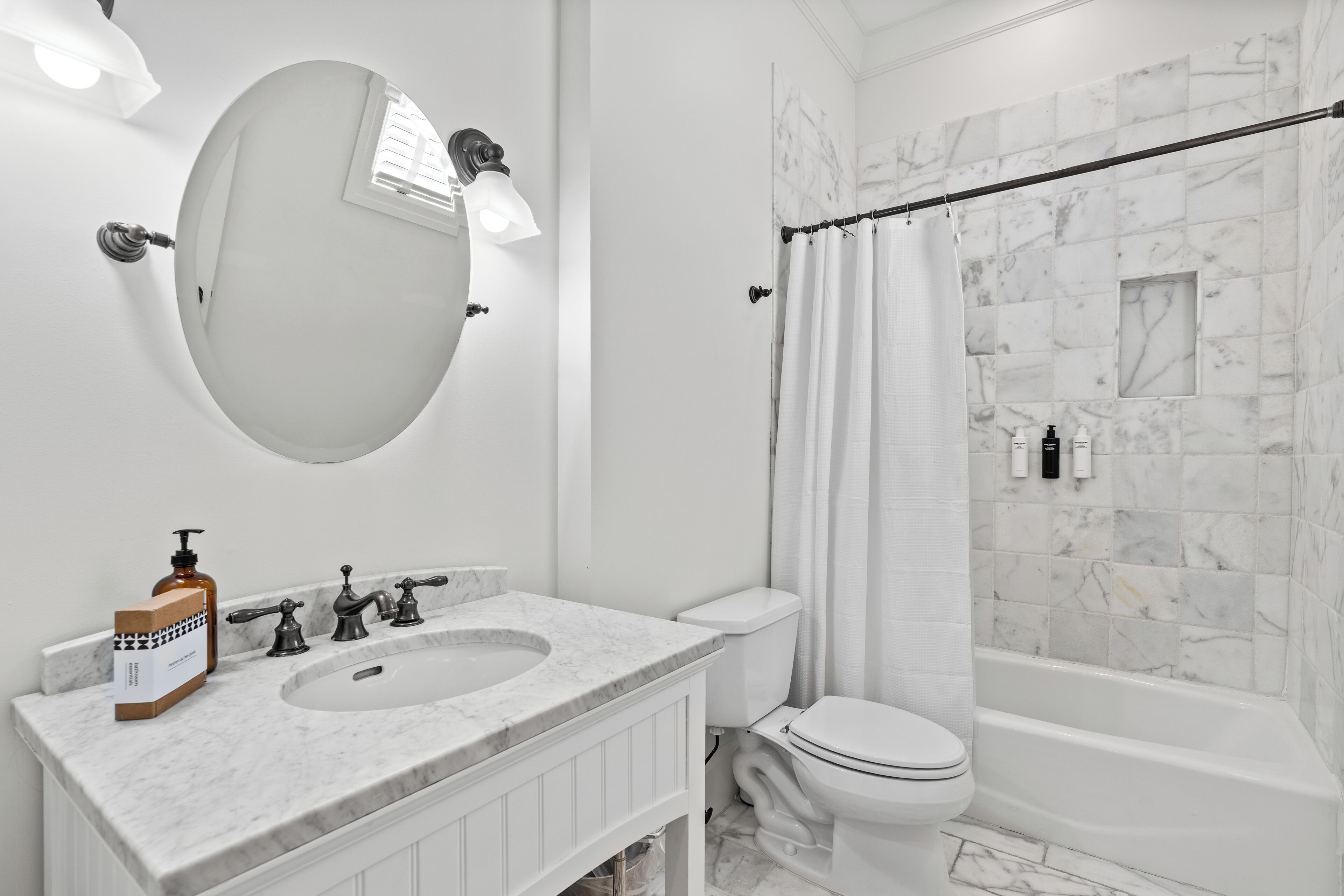 A bathroom with a marble sink, a toilet, and a bathtub with a shower curtain.