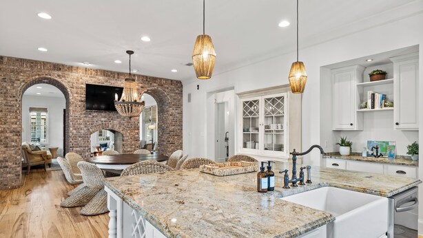 A kitchen with a large island, white cabinetry, and a brick wall. - Family Home | Beach Access | Private Guest House (Inlet Beach)