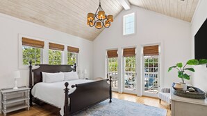 A bedroom with a large bed, wooden ceiling, and a view of the outdoors through large windows. - Family Home | Beach Access | Private Guest House (Inlet Beach)