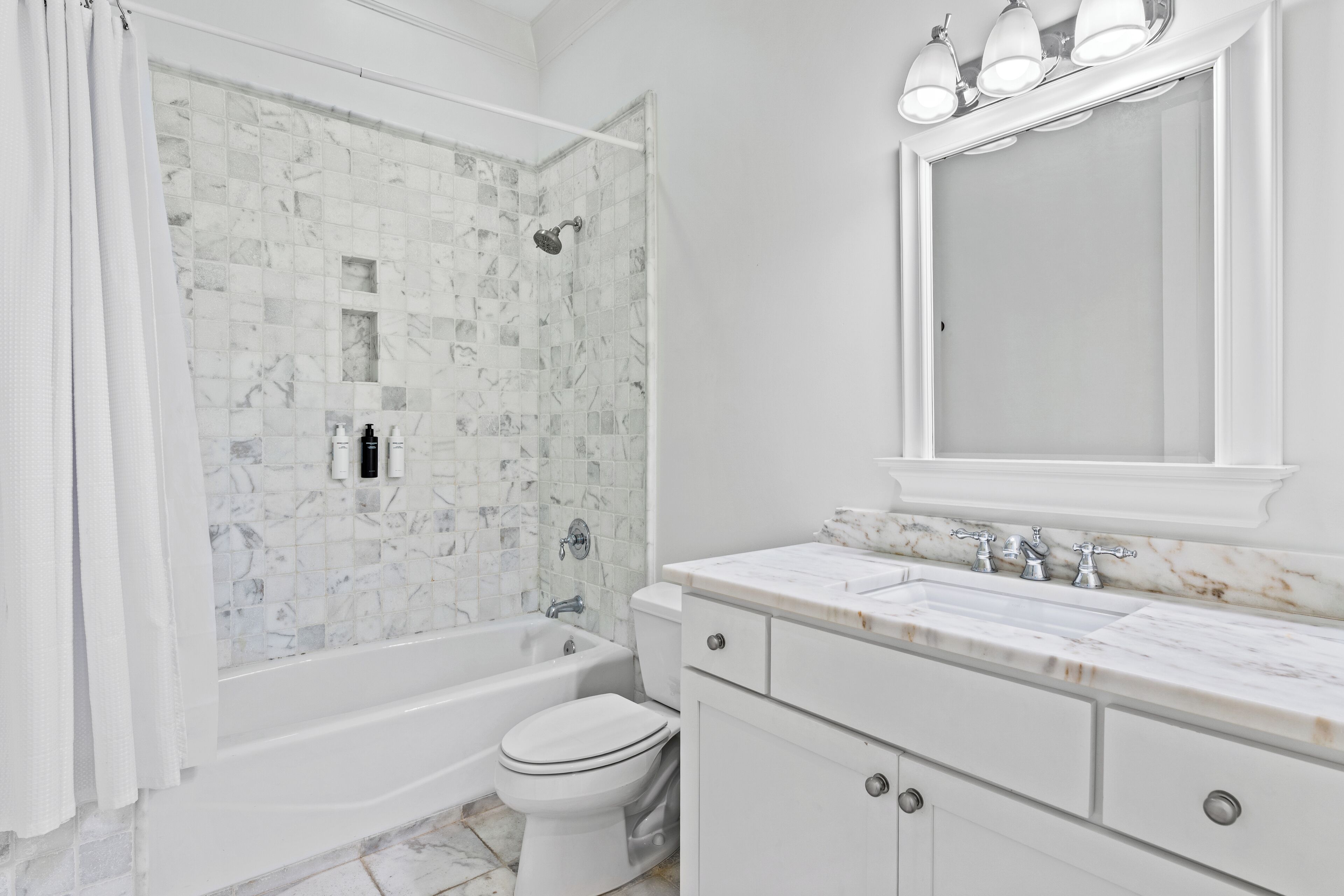 A bathroom with a shower, toilet, and vanity with a mirror.