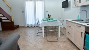 Una cocina moderna con una mesa de comedor para dos personas, horno empotrado y una escalera que sube a un nivel superior.