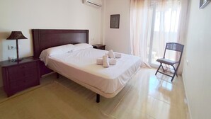 Ein ordentlich eingerichtetes Hotelzimmer mit einem Bett, einem Sessel, einem Nachttisch und einer Lampe.