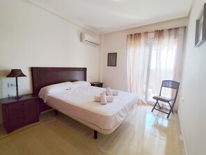 Ein ordentlich eingerichtetes Hotelzimmer mit einem Bett, einem Sessel, einem Nachttisch und einer Lampe.