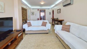 Ein Wohnzimmer mit zwei weißen Sofas, einem Fernseher und einem Kamin.