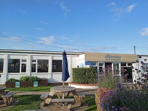 Enjoy a casual dining experience at The Boathouse Bar & Restaurant, surrounded by a beautiful garden with a picnic table and benches.