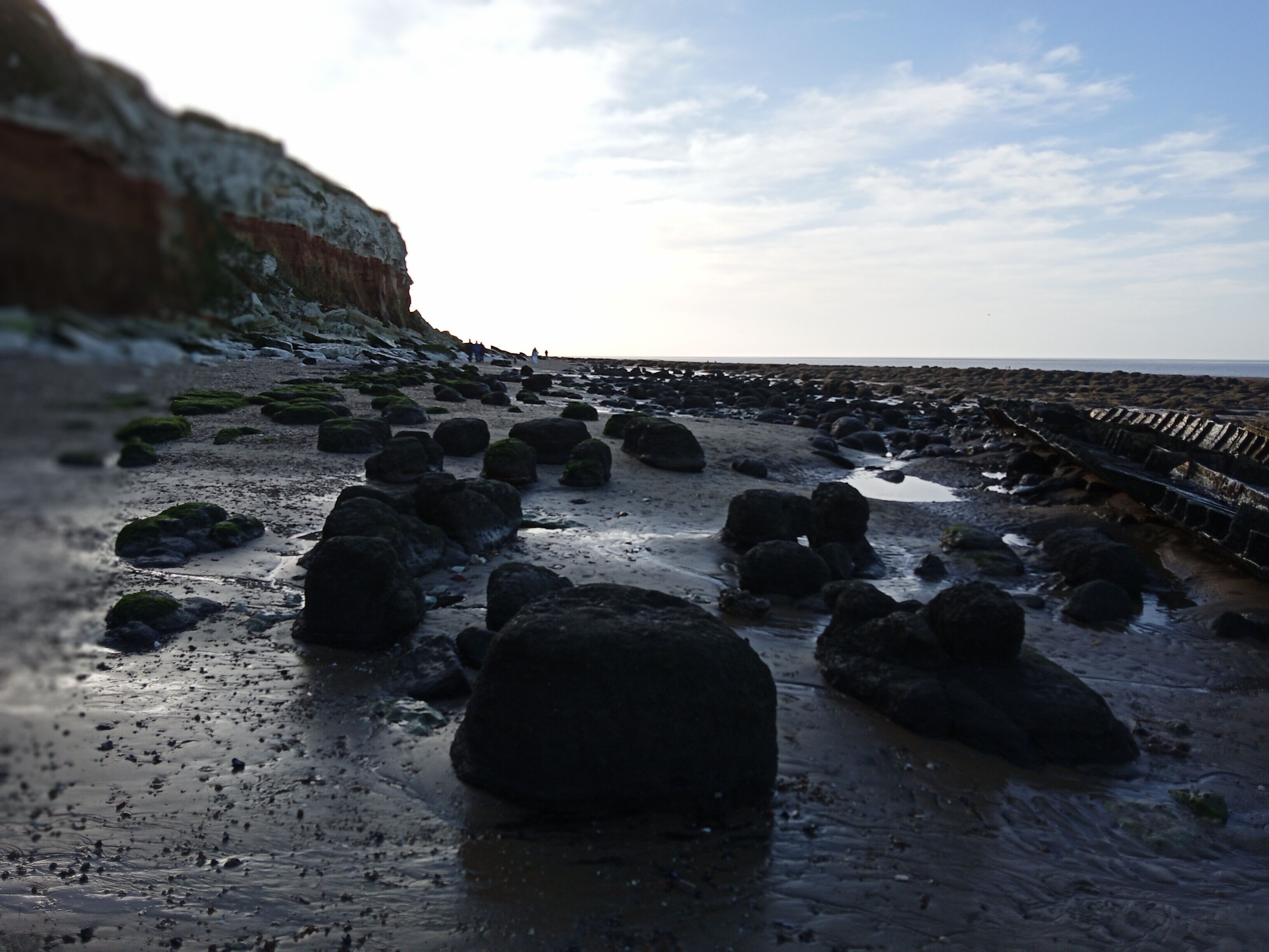 A rocky beach with large boulders and a wooden walkway.