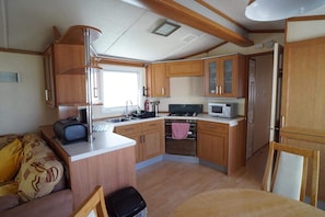 Compact kitchen with microwave, gas stove, and sink, offering ample storage and workspace.